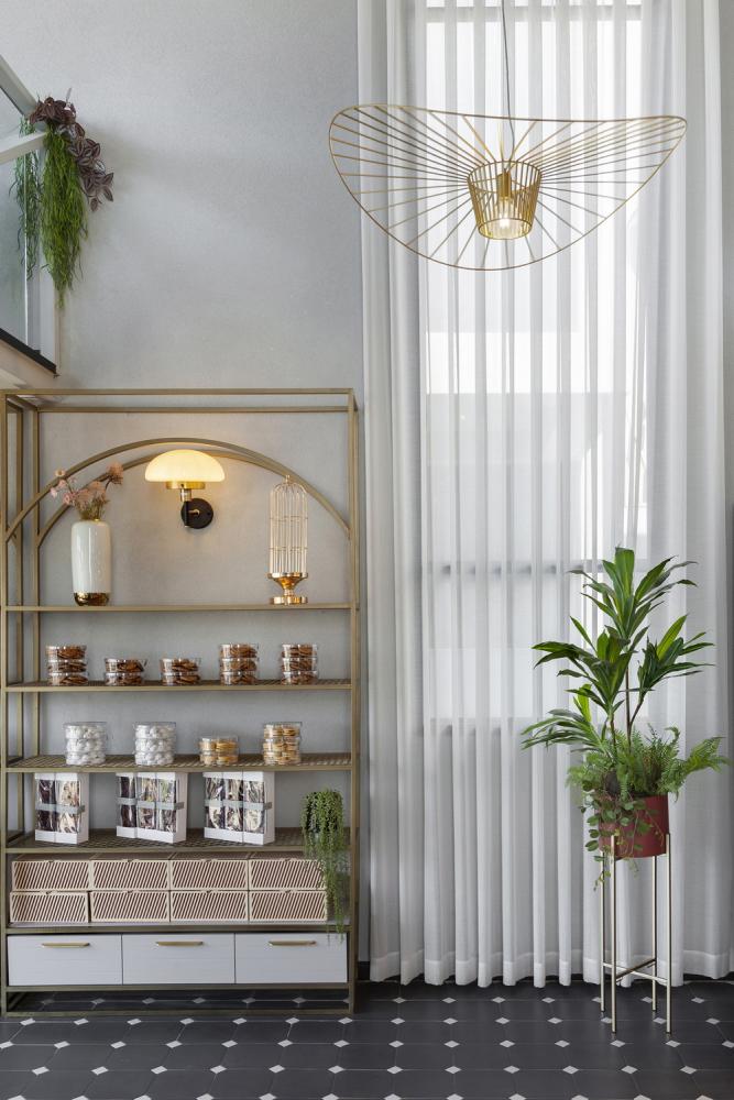 מדפי תצוגה לעוגיות בגימור זהב בצד וילון נשפך לבן